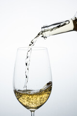 white wine glass with bottle pouring the liquid on a light background