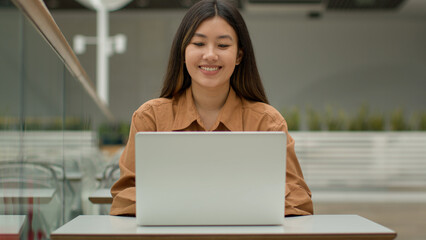 Female office employee Asian woman open laptop in cafe start online job with computer smiling ethnic chinese korean girl student freelancer executive manager ceo employer studying in co-working space