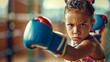 Determined kid boxer in gym space. Girl in boxing gloves practicing boxing punches. Concept of physical education, youth sports, childhood activity, active lifestyle, energetic pastime