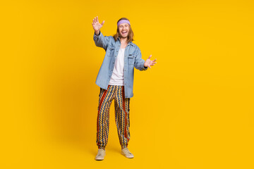 Sticker - Full body photo of attractive young hippie man stretch hands hold empty space wear trendy denim outfit isolated on yellow color background