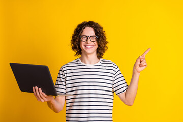 Sticker - Photo of nice young man hold laptop direct finger empty space wear striped t-shirt isolated on yellow color background