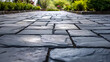 paving black stones of a slate driveway, City sidewalk, blur effect with plants in background, Architectural development, urban and architectural landscape , street floor surface
