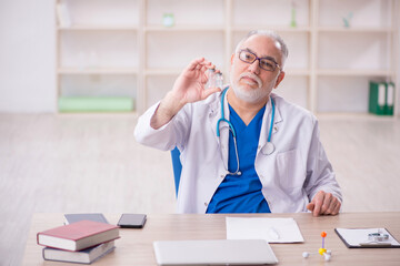 Wall Mural - Old male doctor working in the clinic