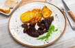 Juicy appetizing baked beef with fried sliced potatoes, decorated with herbs