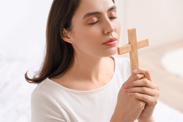 Wall Mural - Young woman with cross praying in bedroom, closeup