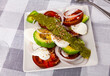 Portion of fresh caprese salad with avocado served on table.