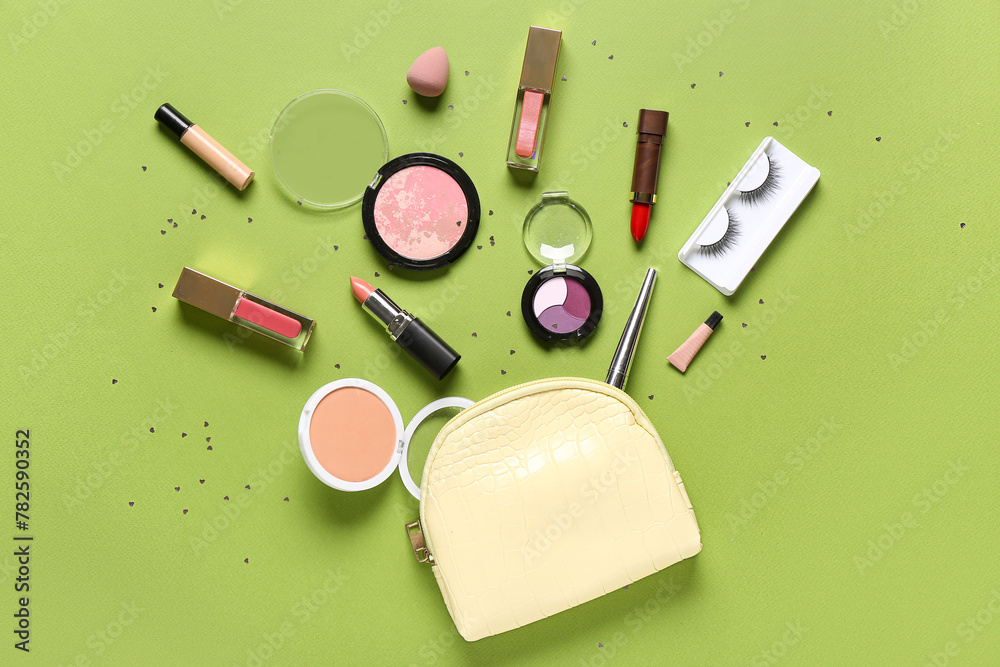 Cosmetic bag with makeup products and confetti on green background