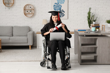 Wall Mural - Beautiful female graduate student in wheelchair with graduation cap, laptop and diploma at home