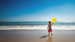 A child playing in the beach with a yellow balloon