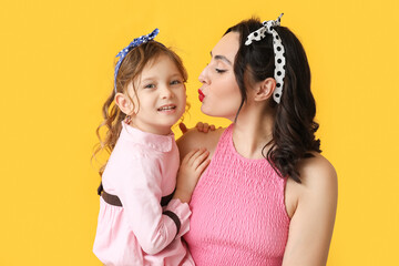 Poster - Beautiful pin-up woman kissing her daughter on yellow background