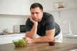 © Pixel-Shot - Sporty young man with salad and muffin on table in kitchen. Weight loss concept