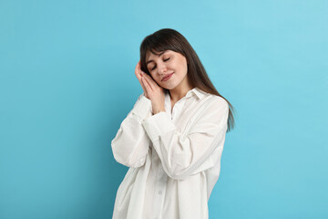 Wall Mural - Woman in pyjama sleeping on light blue background