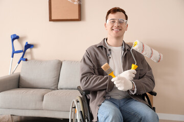 Sticker - Young man in wheelchair with paint roller and brush during repair at home