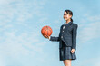 青空の中でバスケットボールを持つ女子中学生・女子高生（部活・スポーツ・運動部・バスケ部）

