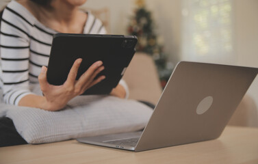 Young attractive asian woman resting using browsing tablet computer on sofa at home, happy girl sitting on couch relax reading digital gadget with excited, communication and lifestyle concept.