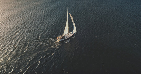 Wall Mural - Yacht sailing on open sea at sun shine aerial. Serene seascape and water transportation. Lonely sail boat cruising at wind sunny day. Nobody nature landscape at cinematic drone shot