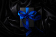 シルクの黒い布の上にある青いリボンをかけたギフトボックス