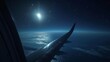 Window view of the airplane wing, gleaming under the moonlight, high above the sea