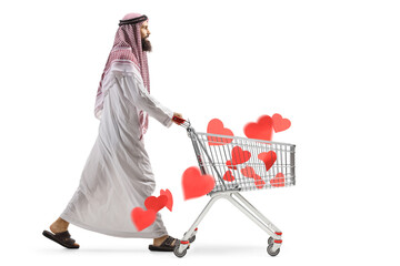 Canvas Print - Full length profile shot of a saudi arab man pushing a shopping cart wit red hearts