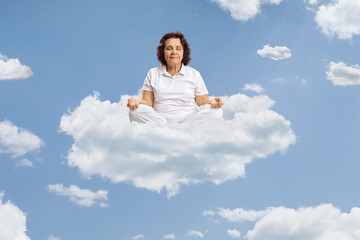 Wall Mural - Elderly woman meditating on a cloud