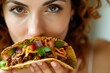 Close-up of a woman indulging in a taco filled with meat and cheese