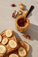 Wall Mural - Peanut paste in a glass jar with toast, on a light background.