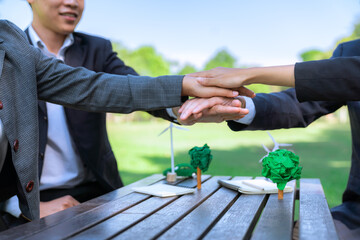 Business people join hand together as teamwork and unity, outdoor business meeting table. Eco-friendly practices and collaboration in corporate social responsibility for greener environment. Gyre