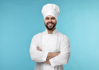 Wall Mural - Happy young chef in uniform on light blue background