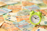 Fototapeta  - Many European euro money bills and alarm clock. Lot of banknotes of European union currency close up