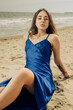 Pretty woman in blue dress sitting on the beach