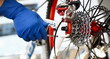 Male repair man bicycle service in blue protective gloves adjusts bike to prepare for the season concept closeup