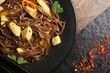 Stir-fry. Tasty noodles with vegetables and meat on dark table, top view. Space for text