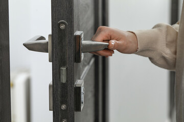 Sticker - Woman opening wooden door indoors, closeup of hand on handle