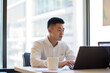 © Andrii  - Focused Asian Professional in Modern Office Environment
