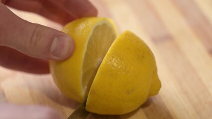 Poster - Cutting lemon in half on wooden table. Cooking with lemon juice, cutting it to squeeze