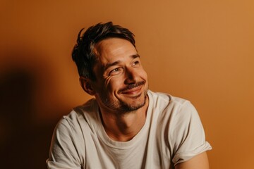 Portrait of a smiling man in a white T-shirt on a brown background