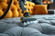 Detailed image of an orange vacuum cleaner deep cleaning a luxury gray tufted sofa with foam