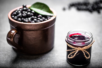 Wall Mural - Aronia jam and fresh berry on stone table.