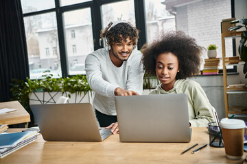 A man and a woman, immersed in their work, passionately focus on a laptop screen in a modern coworking space.