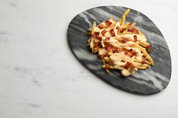 Delicious French fries with bacon and cheese sauce on white marble table, top view. Space for text