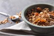 Tasty granola in bowl and napkin on gray table, closeup