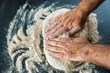 Fototapeta Uliczki - Männerhände kneten massieren und rollen einen Teig auf einer Arbeitsoberfläche in der Küche zu Hause aus