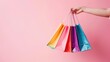 © YauheniyaA - Hands, shopping bags and purchase on pink for fashion, discount or sale. Hand of shopper holding bag of gifts, present or luxury retail products on copy space