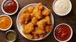 A white plate with crispy fried chicken nuggets served alongside an assortment of dipping sauces