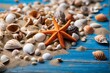 Beach scene concept with sea shells, starfish and sand on a blue wooden background.