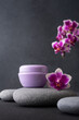 Lilac cosmetic cream jar, product mockup on dark background with orchid flower