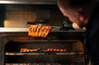 close-up of a professional kitchen a chef in a black jacket near a hot grill oven turns over ribs