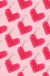 Repetitive pattern made from beaded heart keychains on a pink background. Creative layout.