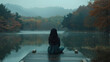 A lone woman sitting in tranquility on a wooden pier by a calm lake, surrounded by the peaceful beauty of autumn foliage.