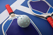 Detail of blue and red pickleball paddles on playing court